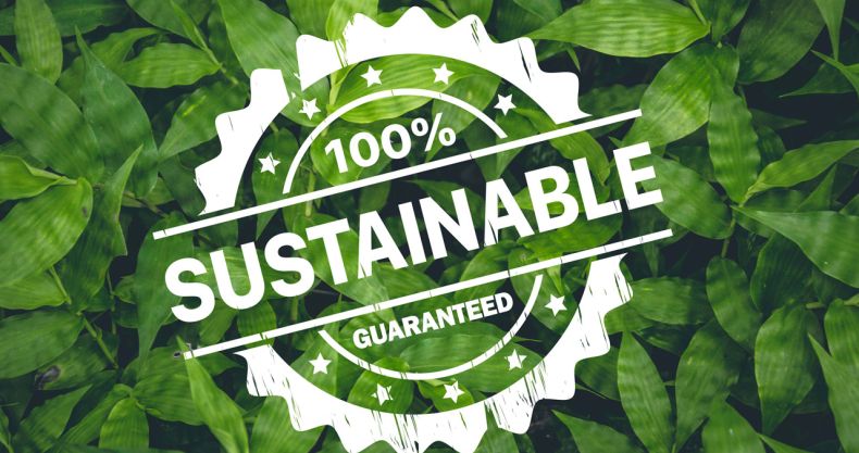 Weißes Greenwashing-Siegel mit Text „100% Sustainable Guaranteed“ auf Hintergrund aus grünen Blättern.